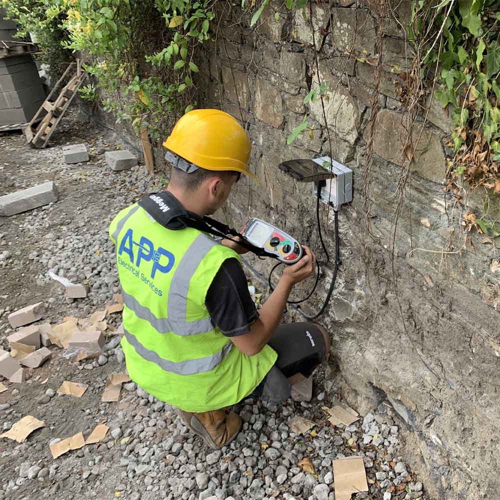 APP Electrical team member conducting electrical tests on outdoor unit.