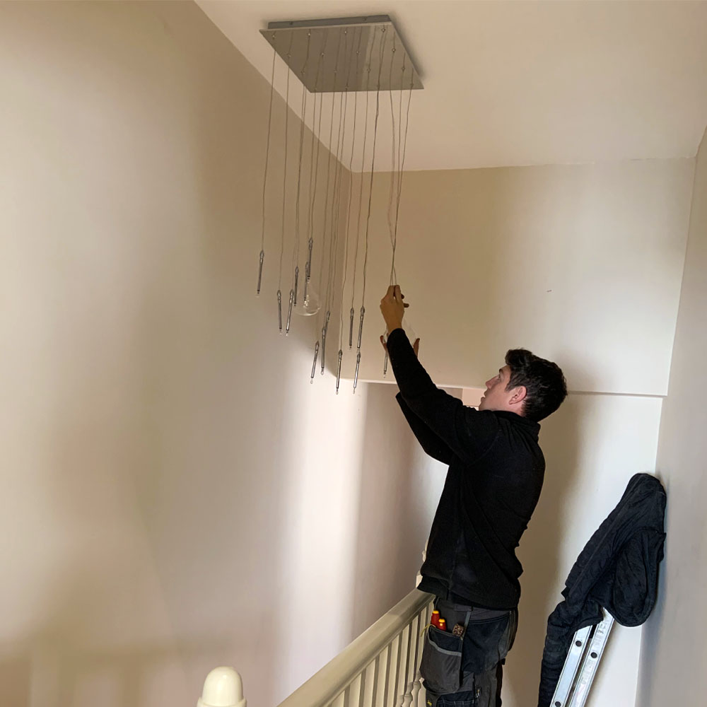 APP Electrical team member Andrew carrying out internal lighting installation above a staircase.